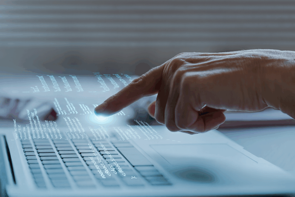 Mano che interagisce con un laptop e codice digitale, simbolo di innovazione e digitalizzazione nei servizi di facility management.